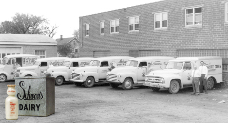 A row of six Schwans trucks with drivers standing next to each