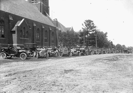 Line of automobiles parked near Catholic Church, Aitkin Minnesota, 1915