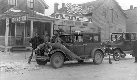 Hunters posed by deer on car in front of Briol Studio, Albany Minnesota, 1925