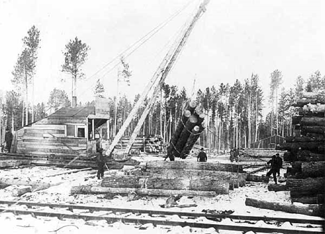 Stacking logs next to railroad tracks near Bena Minnesota, 1910's
