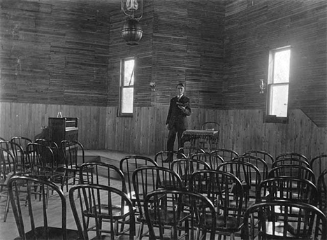 Edward McCann standing in the Methodist Episcopal Church, Big Falls, 1909