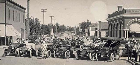 Cars, people and a clown on a Deerwood street, 1914