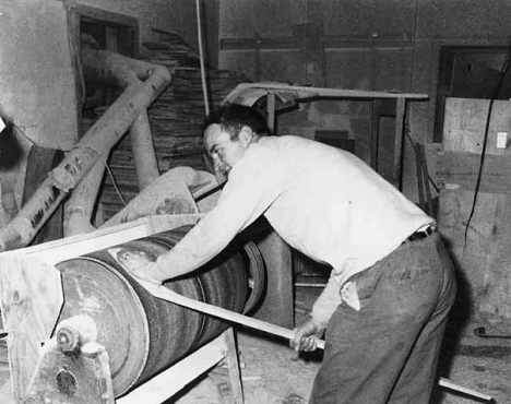 Roger Christian using barrel sanding for smoothing out hockey sticks at Christian Brothers hockey stick factory's first plant, Warroad Minnesota, 1964.