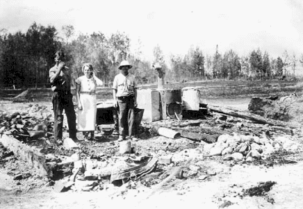 Mr. and Mrs. John Halonen and their hired man viewing ruins of their barn after forest fire, Aurora, Minnesota, 1936